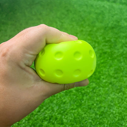 Hand squeezing a green foam practice pickleball