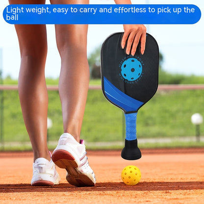 Ball picker on the end of a pickleball paddle handle picking up a ball from the court